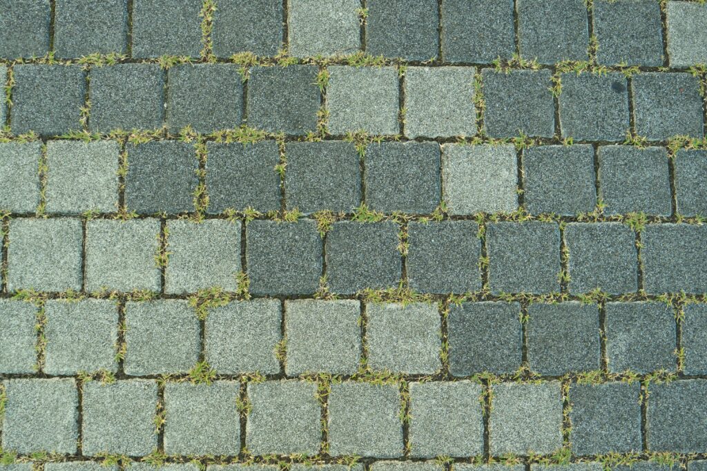 Close-up of a stone paved sidewalk with grass growing between the stones in Toyohashi, Japan.